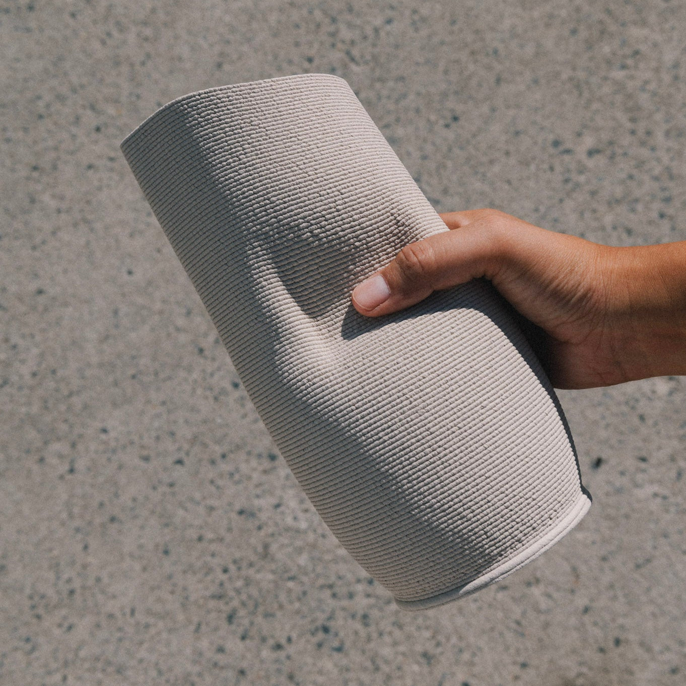 Hand holding 3D printed ceramic pitcher in natural stoneware clay, minimal design, handmade in Berlin, showcasing textured surface and modern form.