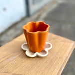 Flora Tray and Flora Cup — 3D printed ceramic flower-shaped cup and underplate handmade in Berlin, stoneware clay with orange glaze, modern design.