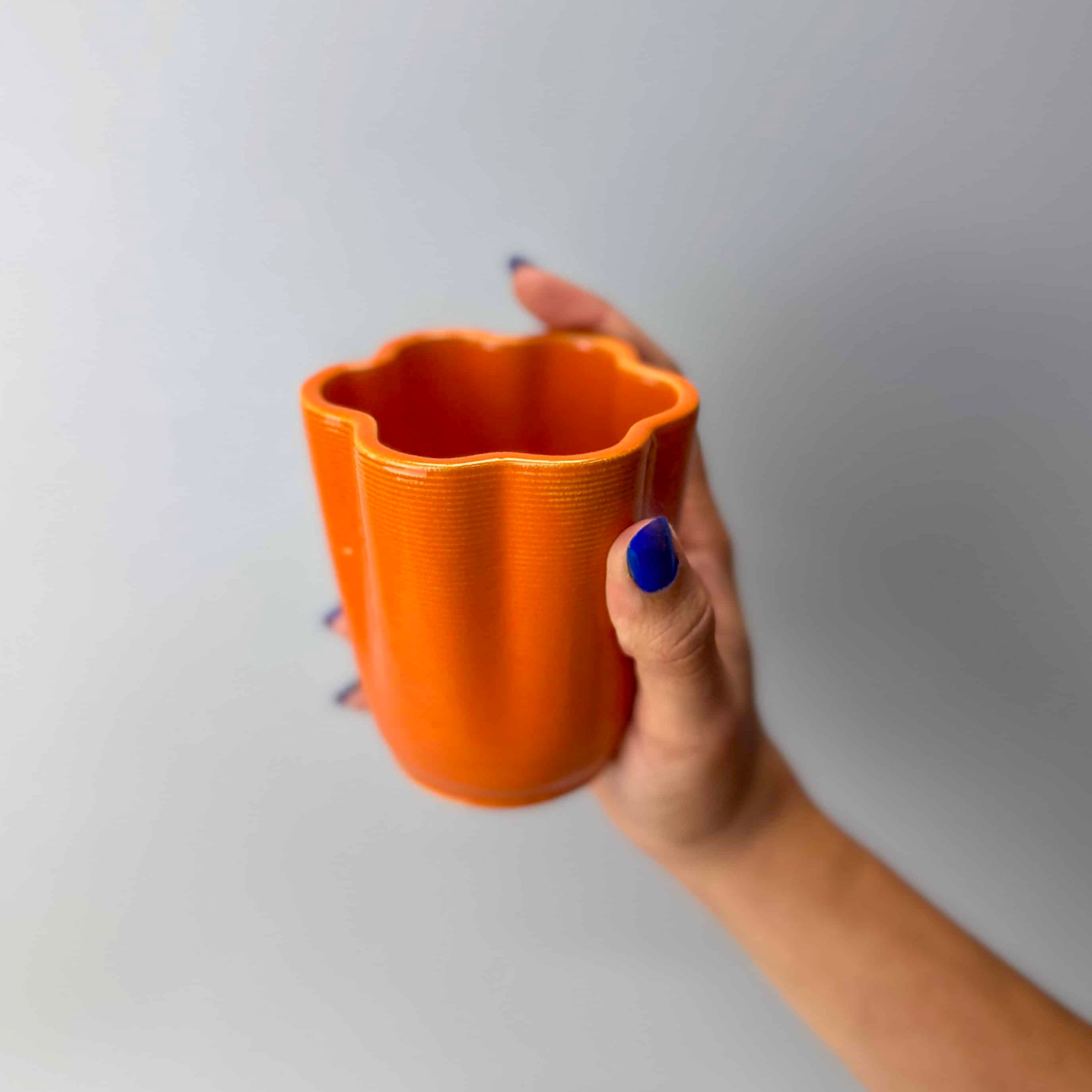 Hand holding Coral Mug 3D printed ceramic coffee cup, handmade in Berlin, natural clay with glossy transparent glaze.