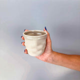 Hand holding Ripple Mug  3D printed ceramic coffee cup, handmade in Berlin, natural clay with glossy transparent glaze.