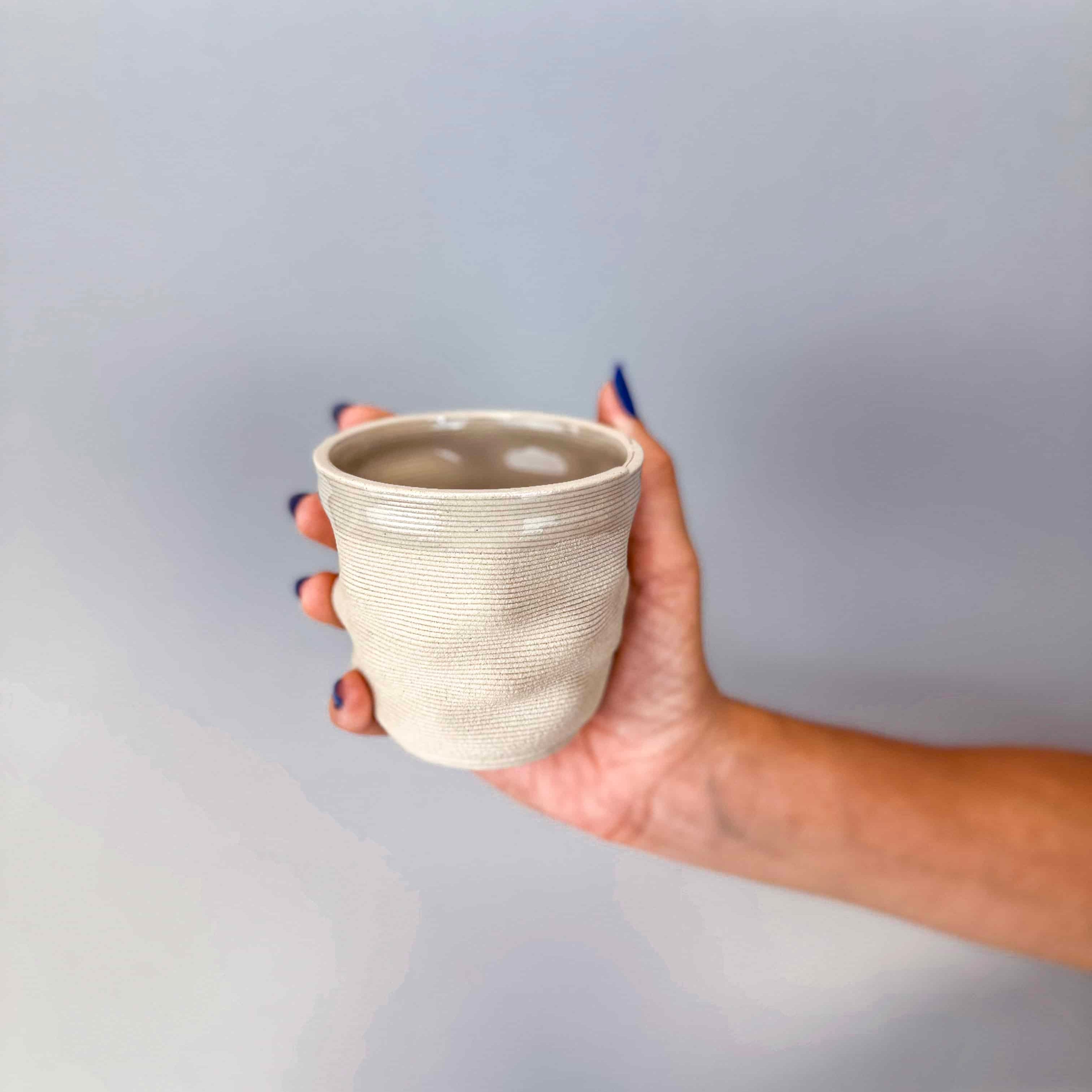 Hand holding Ripple Mug  3D printed ceramic coffee cup, handmade in Berlin, natural clay with glossy transparent glaze.
